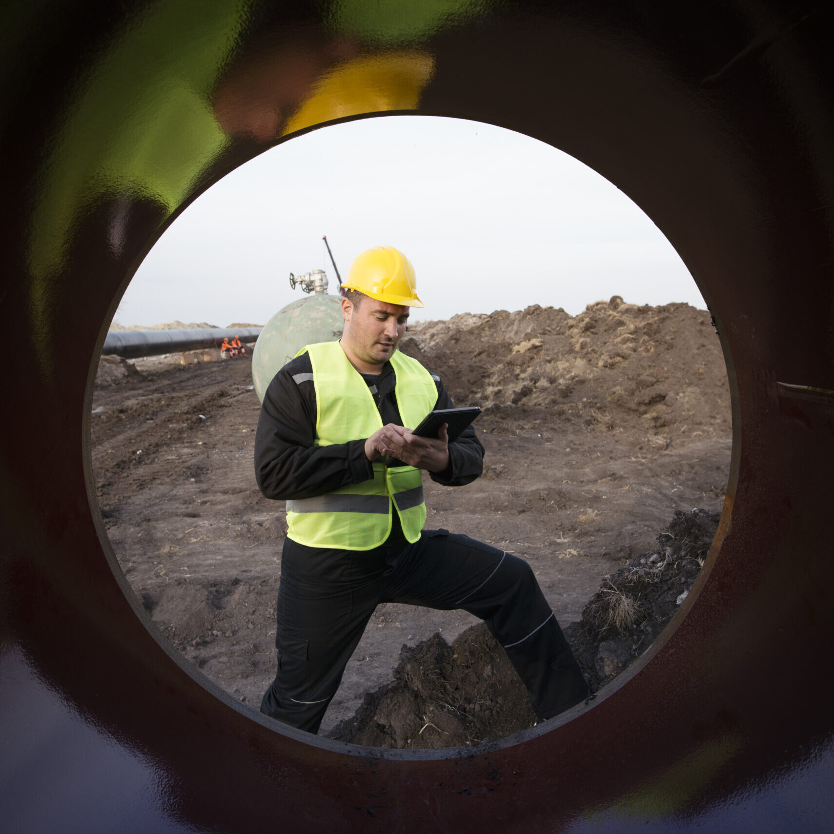Shot of an oilfield worker checking quality of gas pipes at construction site.